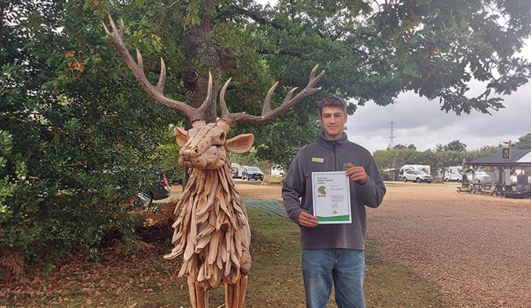 Cameron stands holding Green Leaf award certificate