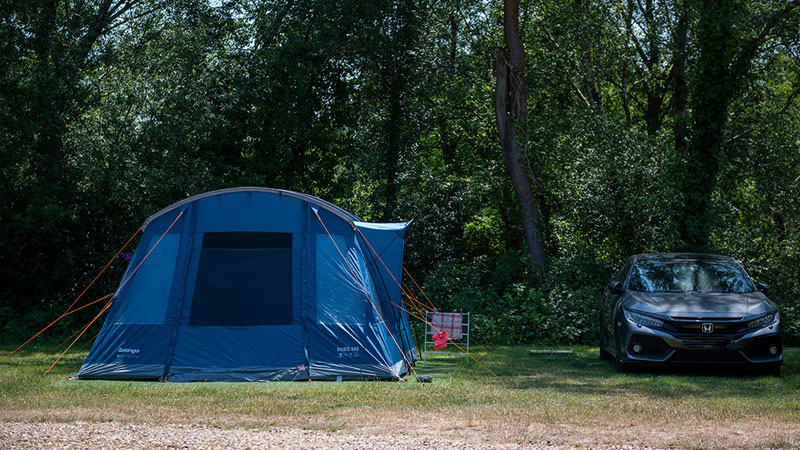 A blue tent pitched alongside a car at Back of Beyond