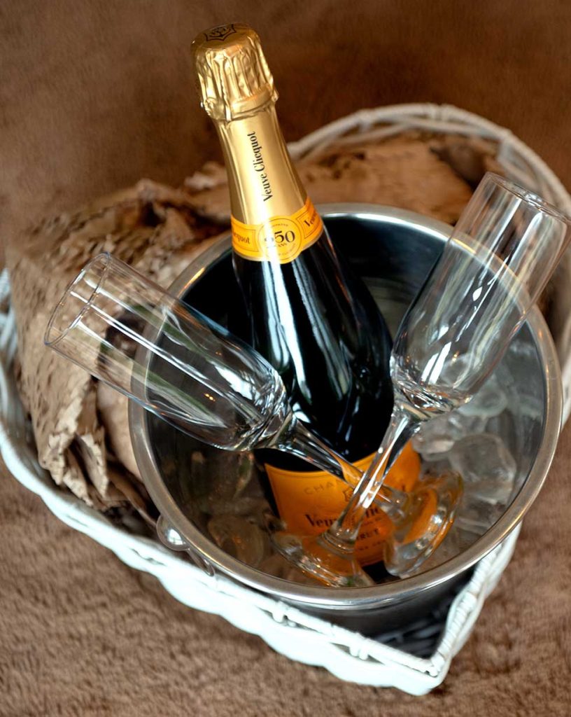 A bottle of champagne and two champagne glasses presented in a metal bucket with ice at Back of Beyond.