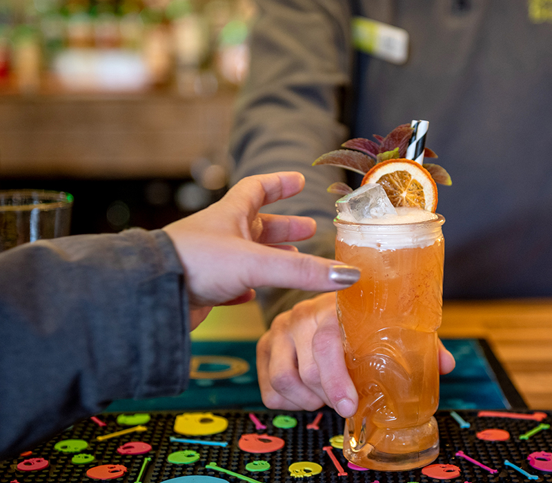 Person reaching for an orange, long cocktail at Monty's Bar