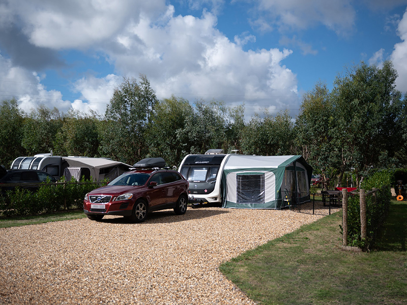 A superior hardstanding fully serviced pitch with a car, caravan and awning on.