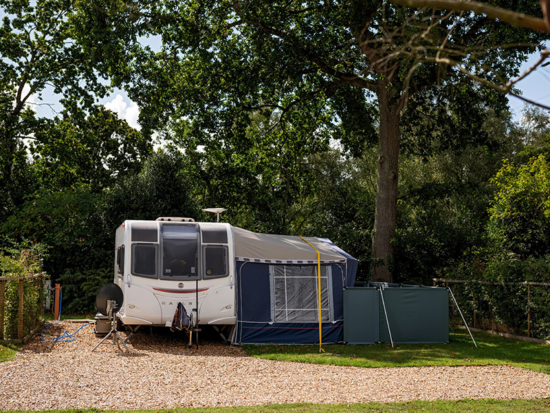 Superior astroturf fully serviced pitch with caravan and awning.