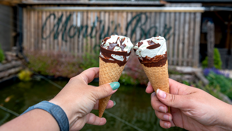 Two ice creams being held outside Monty's Bar sign