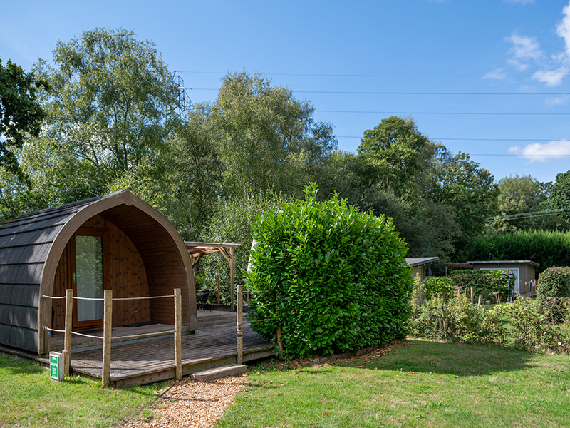 Glamping pod in the foreground with a lodge in the background