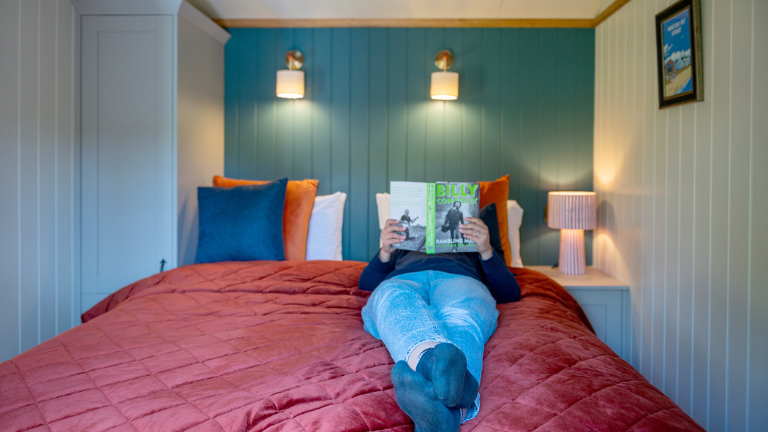 A person lays on the bed in Bramble reading a book