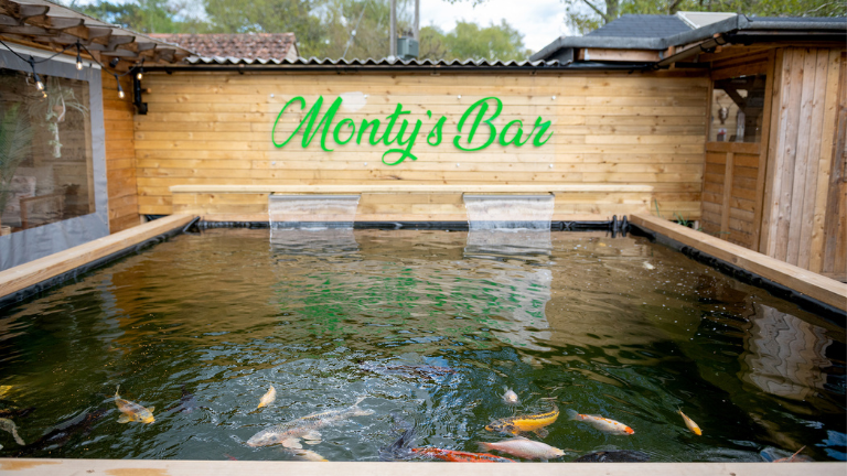 Monty's Bar sign set behind the large pond with koi carp